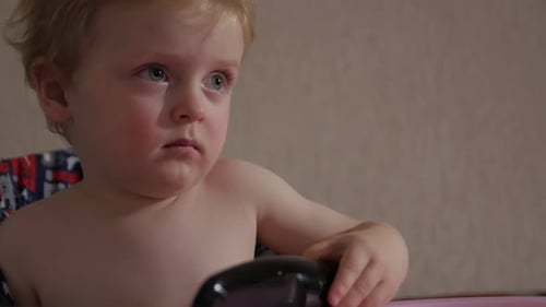Kleiner Junge mit Fernbedienung vor dem Fernseher