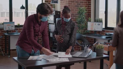Employée enceinte travaillant avec un homme sur des graphiques commerciaux