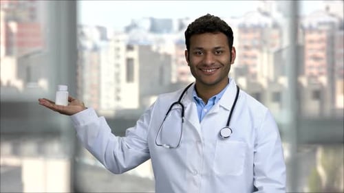 Smiling Doctor Holding Pill Bottle in Modern Clinic
