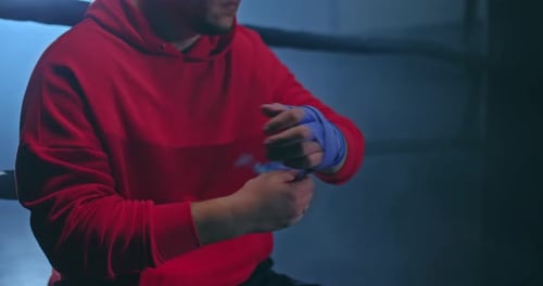 Man Wrapping Hands with Tape in Boxing Ring