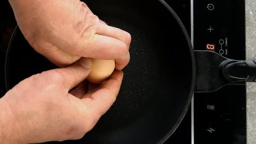 Egg Cracking Into a Frying Pan, Top Down Shot