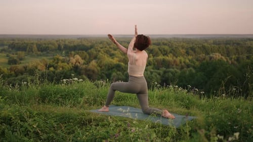 Woman Practicing Yoga on Grassy Hill at Sunset