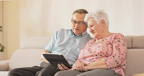 Senior Couple Using Tablet on Couch Indoors