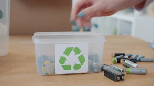 Person Recycling Used Batteries Into Container At Home