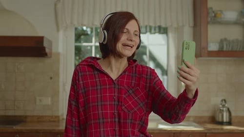 Cheerful Woman Video Chatting on Smartphone in Kitchen