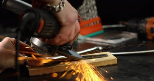 Close up Locksmith works with grinder machine, fly bright sparks.