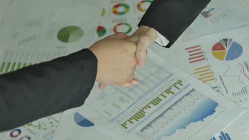 Business People Analyze Charts and Shake Hands