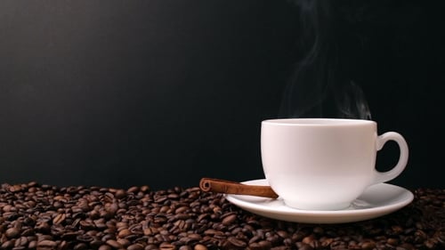 Hot Coffee Steaming in Mug on Coffee Beans