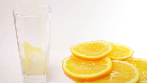 Orange Juice Being Poured into Glass with Slices
