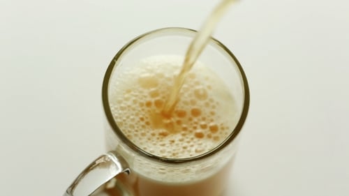 Foamy Beverage Poured into Clear Glass Mug