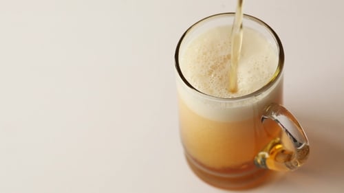 Foamy Beer Being Poured into Clear Glass Mug