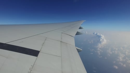 Flügel eines Flugzeugs, das in blauem Himmel fliegt 13