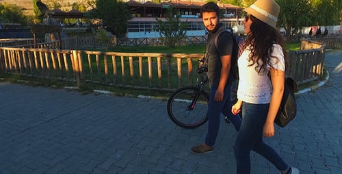 Young Couple Walks with Bike Through Beautiful Park