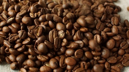 Fresh Coffee Beans Pouring Onto Fabric Surface