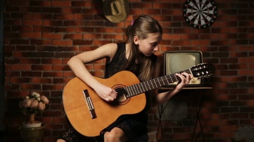 Teen Girl Plays Guitar in Decorated Room