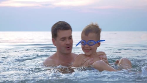 Father and Son Splashing in Ocean at Sunset