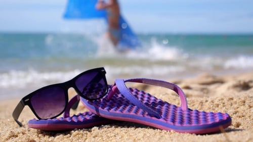 Tropischer Urlaub am Strand mit Flip-Flops und Sonnenbrille