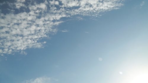 Airplane Flying Across Blue Cloudy Sky