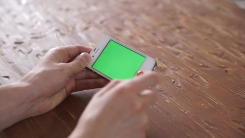 Hands Holding Phone with Green Screen Display