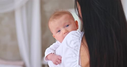Mother Holding a Baby Inside of a Home