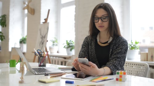 Young Woman Uses Phone at Bright Desk