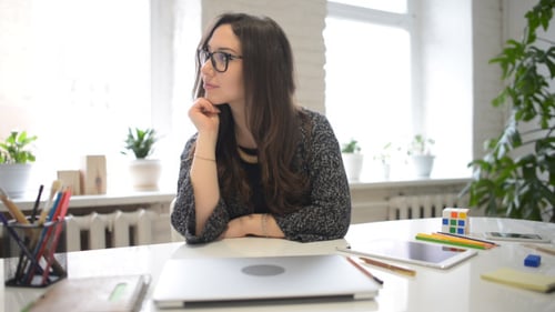 Woman Thinking at Desk with Laptop Computer