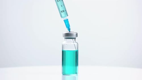 Syringe Draws Teal Liquid from Vial, Close Up