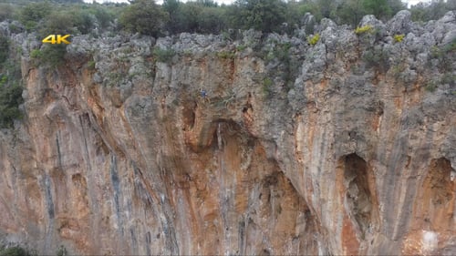 Rock Climber Ascends Steep Cliff Wall During Daytime