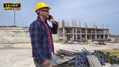 Construction Worker Talking on Cellphone at Building Site