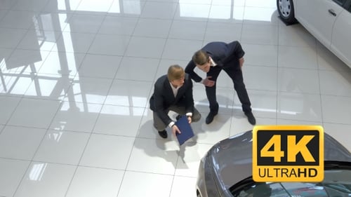 Salesman Assisting Customer In Car Showroom