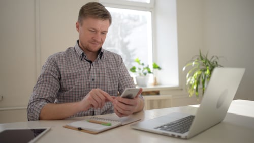 Blond Man Using Cellphone in Bright Home Office
