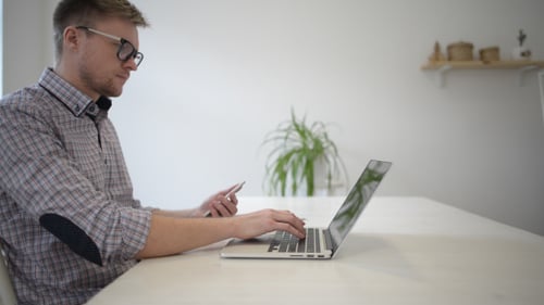 Young Adult Using Laptop and Smartphone at Desk