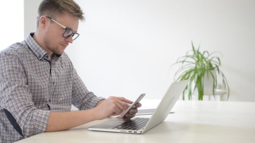 Young Adult Uses Smartphone at Desk