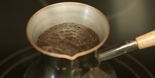 Stirring Coffee in a Metal Pot on Stove