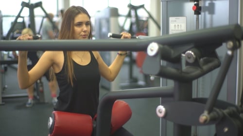 Woman Exercising on Lat Pulldown Machine at Gym