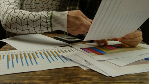 Statistiken, auf die auf einem Schreibtisch hingewiesen wird. Hände des Geschäftsmannes und der Geschäftsfrau.