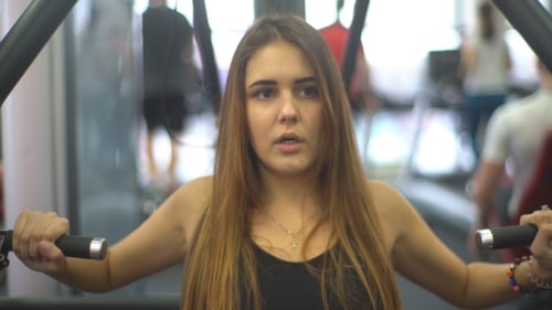 Woman Works Out on Machine at Gym