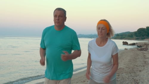 Mature Couple Jogging On The Beach