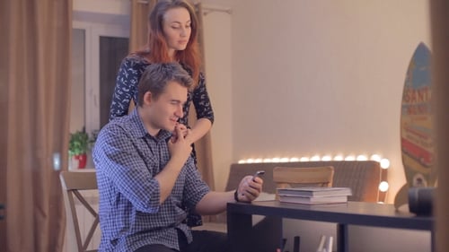 Smiling Couple Looking at Smartphone Together Indoors