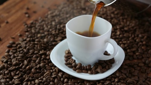 Coffee Being Poured into White Cup with Beans