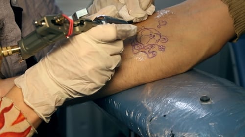 Tattoo Artist Inking Teddy Bear on Arm