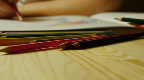 Child Drawing with Crayons on Wooden Desk
