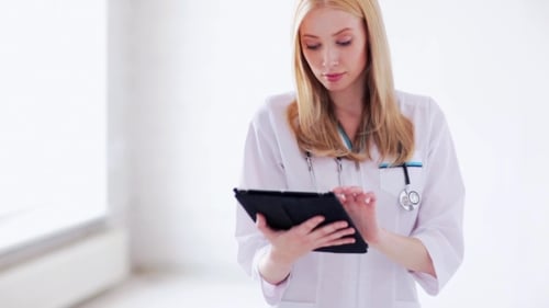 Young Woman Doctor Using Tablet in White Room