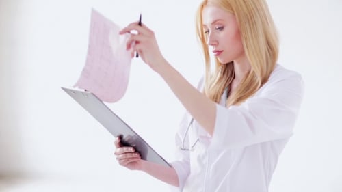 Female Doctor Reading Documents At Hospital 57