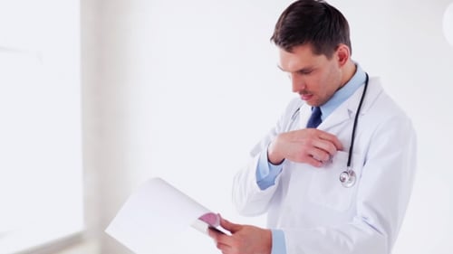 Male Doctor Reading Medical Documents At Hospital 52
