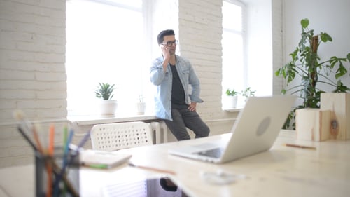 Young Adult Man Talking on Smartphone in Bright Office