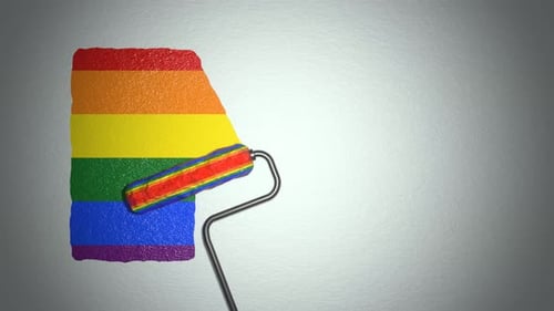 El
rodillo pinta la pared con colores de bandera arcoíris.