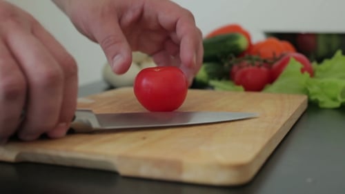 Slicing Tomato on Cutting Board with Fresh Vegetables