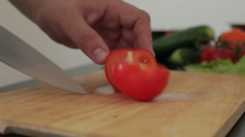 Tomato Being Sliced on a Wooden Cutting Board