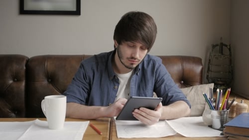 Young Adult Using Tablet Device at Table